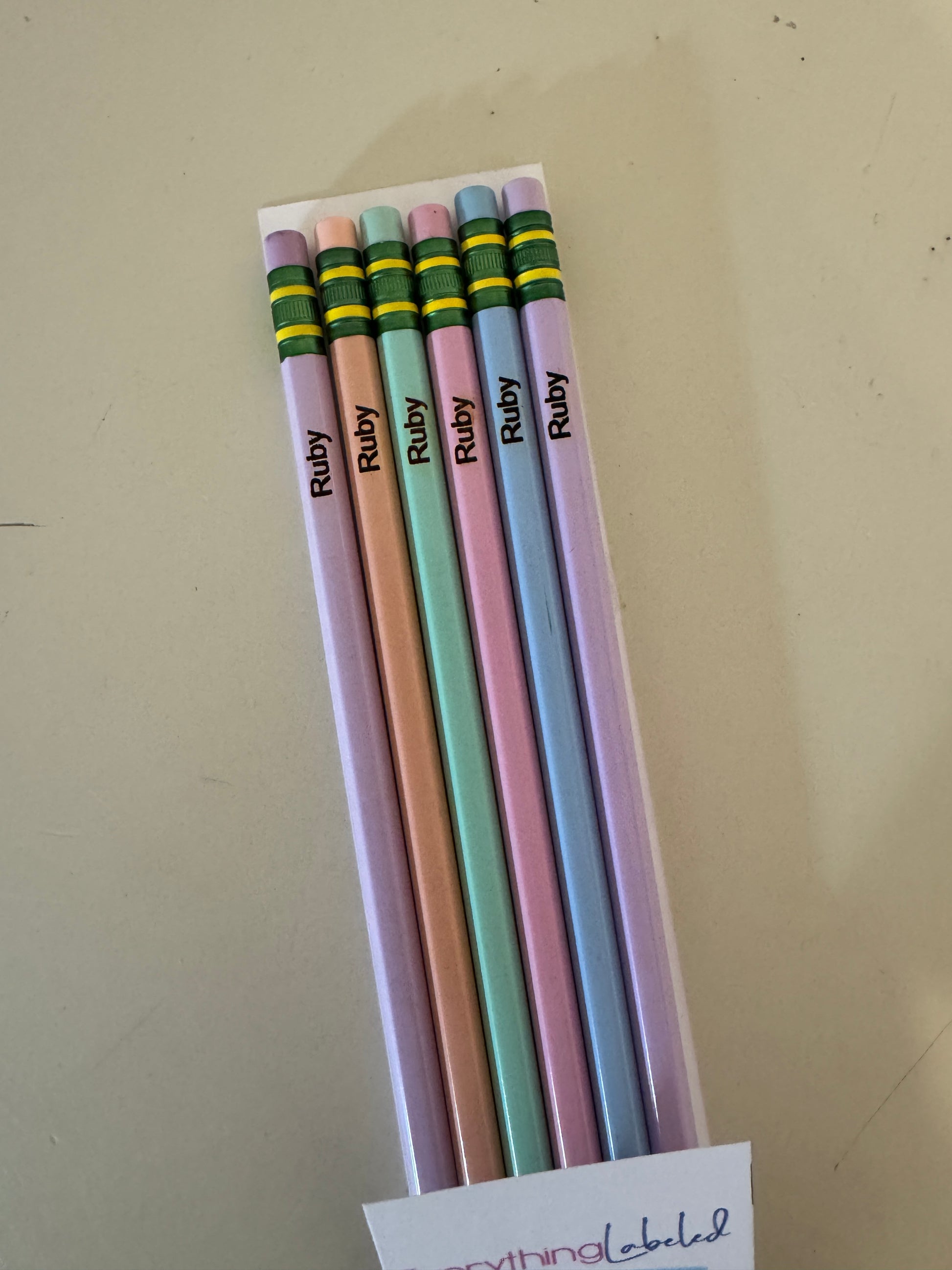 Set of colorful pencils with 'Ruby' branding on a beige surface