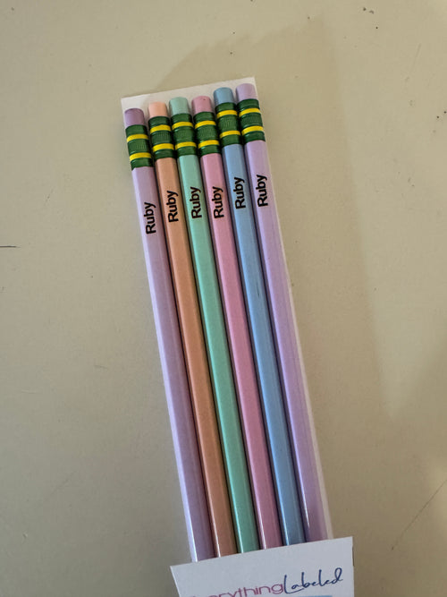 Set of colorful pencils with 'Ruby' branding on a beige surface