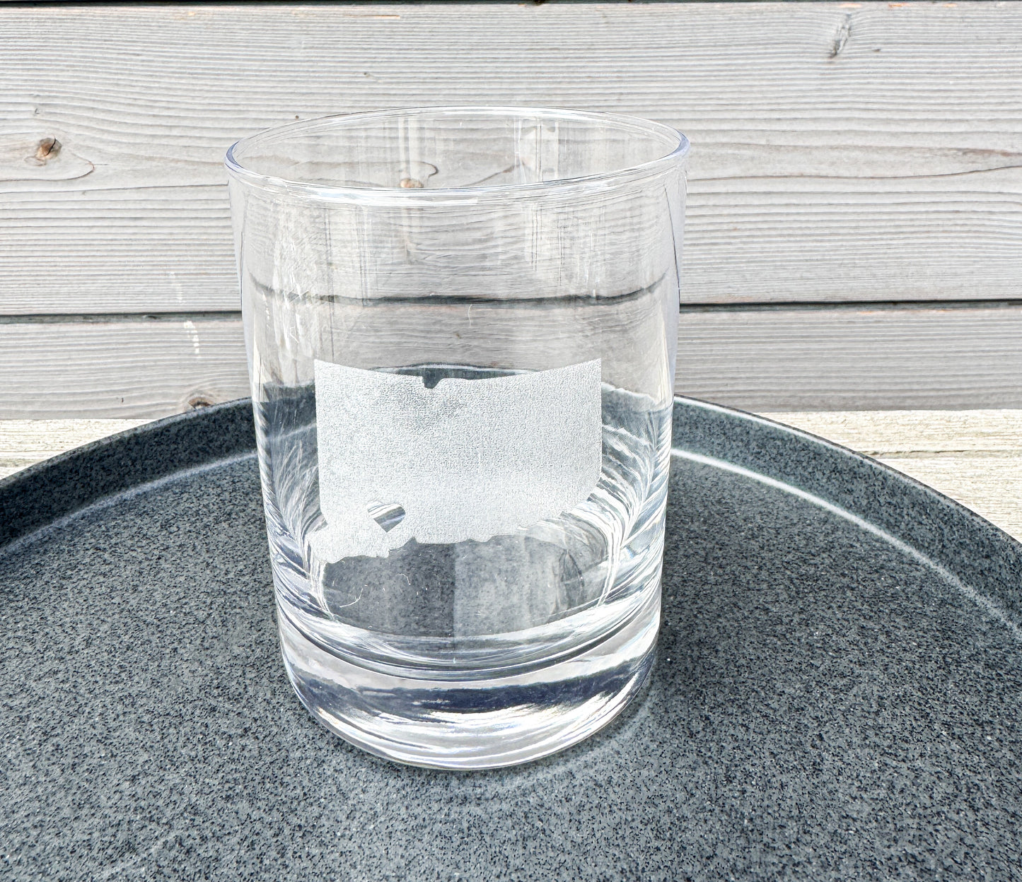 Clear glass on a dark gray tray with a wooden surface in the background