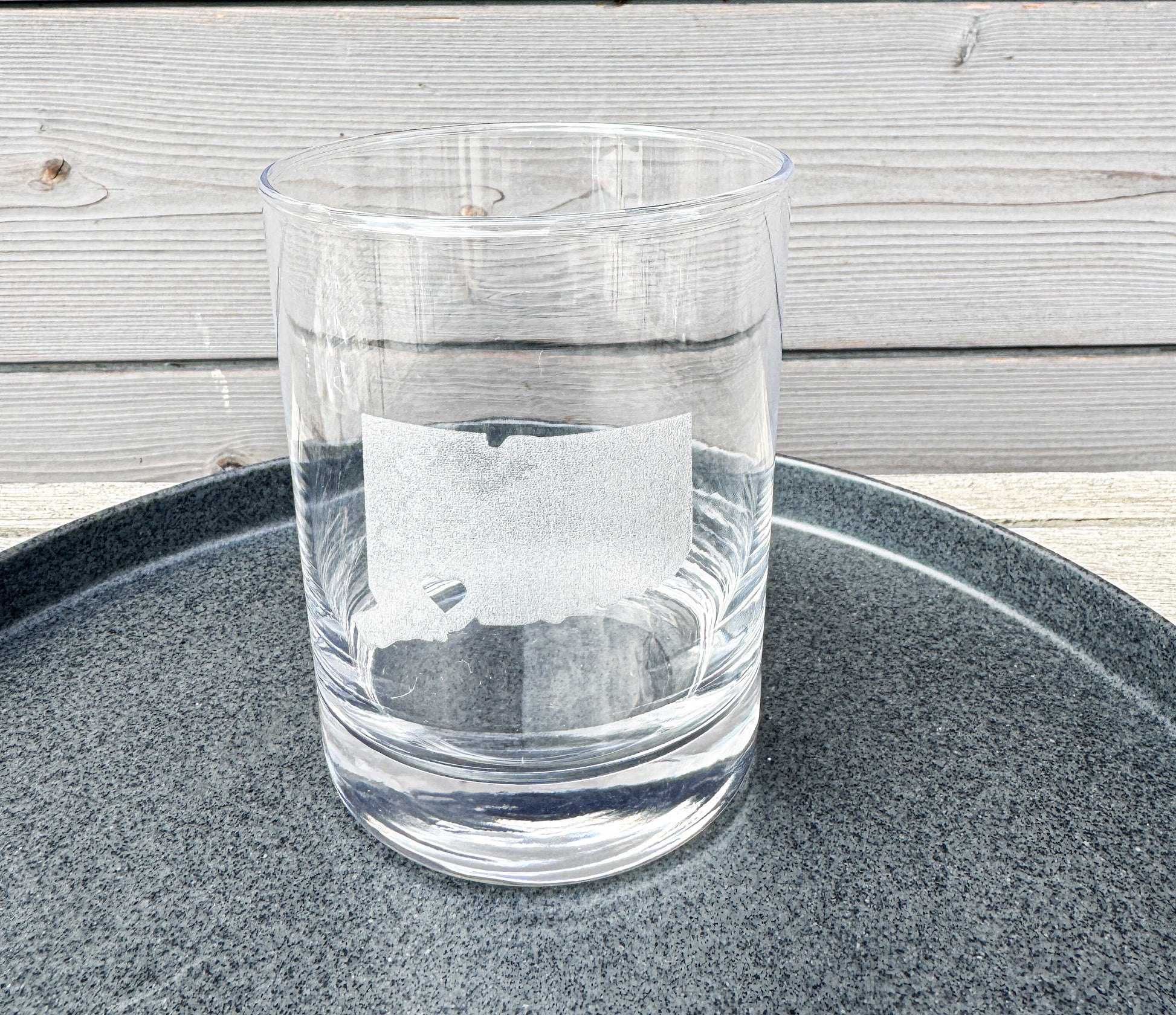 Clear glass on a dark gray tray with a wooden surface in the background