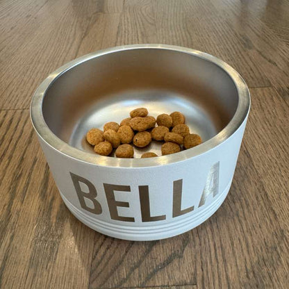 Stainless steel pet bowl with 'BELLA' on a wooden floor