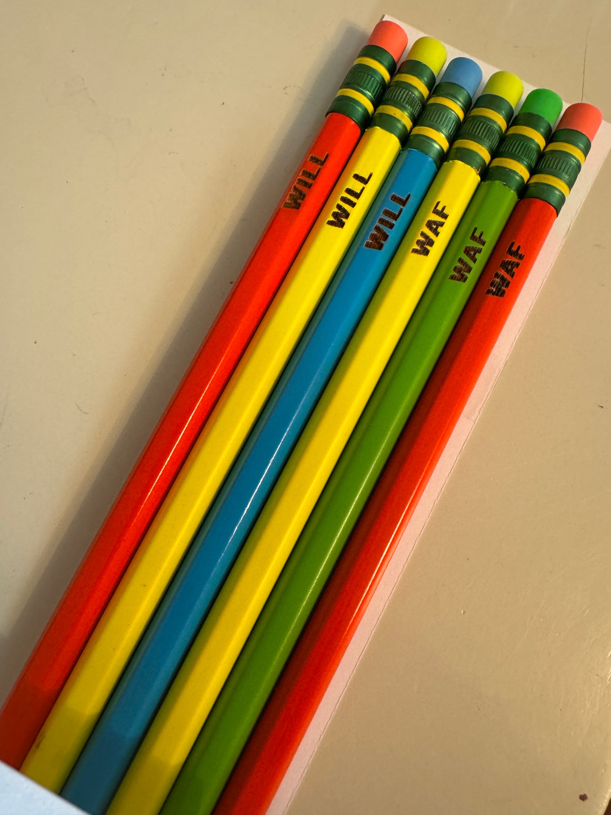 Colorful pencils with labeled tips on a beige surface