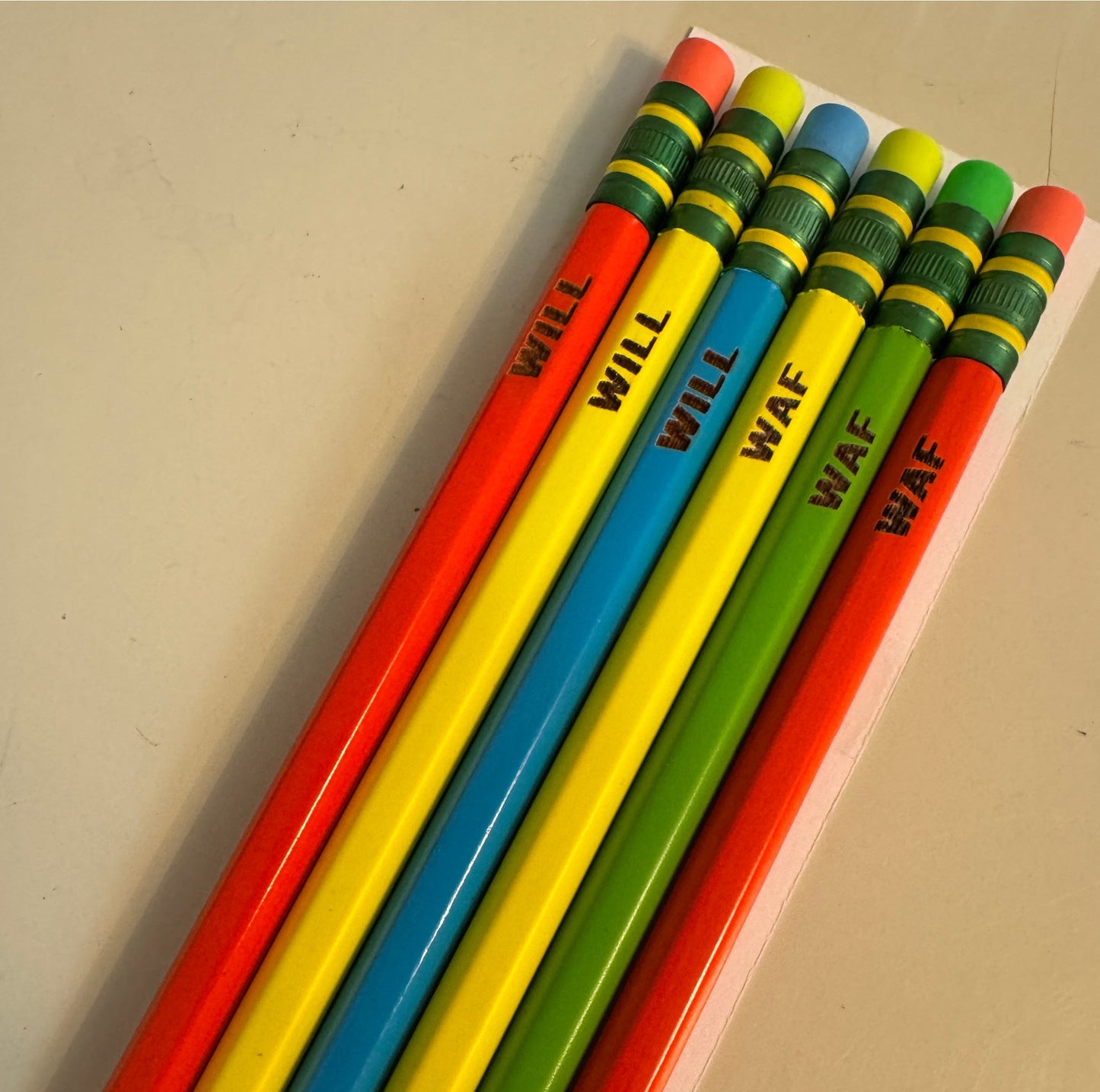 Colorful pencils with labeled tips on a beige surface