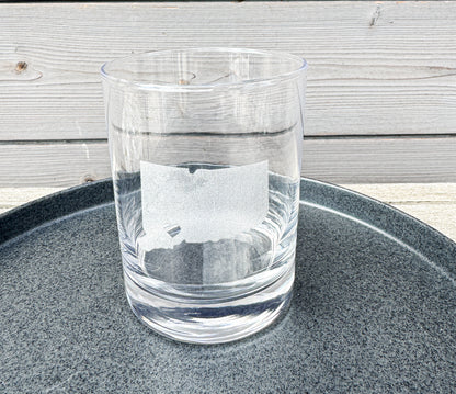 Clear glass on a dark gray tray with a wooden surface in the background