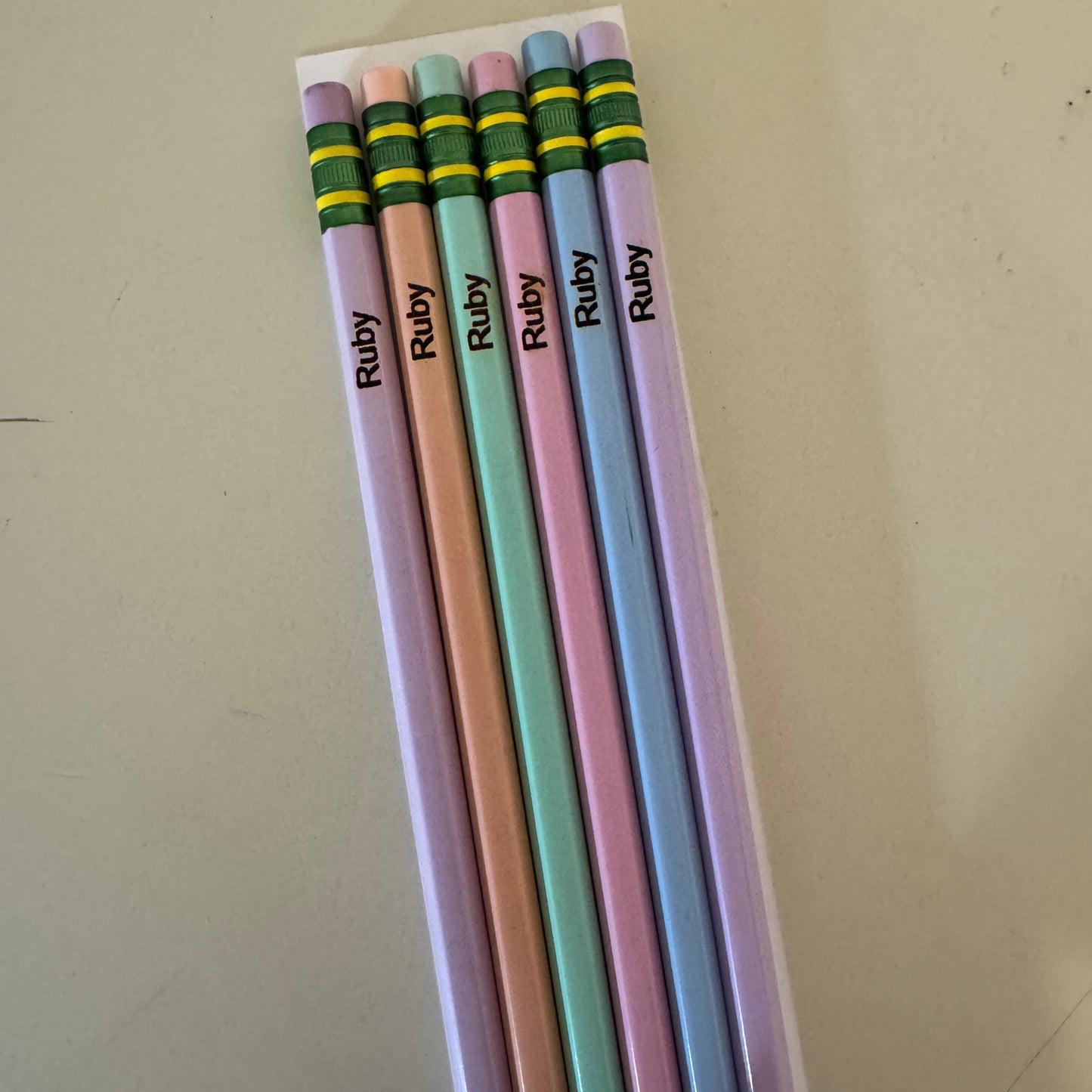 Set of colorful pencils with 'Ruby' branding on a beige surface